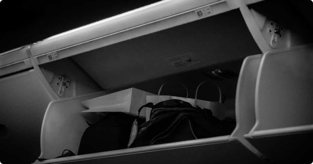 Carry-on spinner suitcase being loaded into an overhead bin — best carry-on luggage for international travel