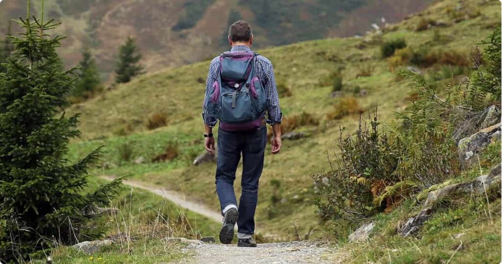 Solo traveler with backpack overlooking vast mountain landscape at golden hour — best solo travel destinations