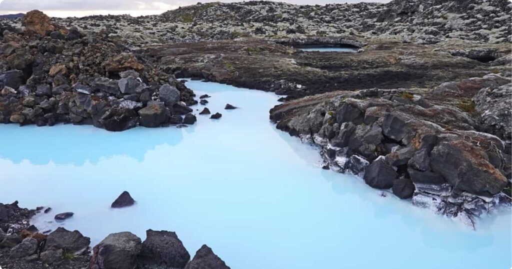 Blue Lagoon Iceland: Complete Guide (Tickets, Tips & What to Expect) Milky-blue geothermal waters of the Blue Lagoon Iceland surrounded by black lava fields and rising steam