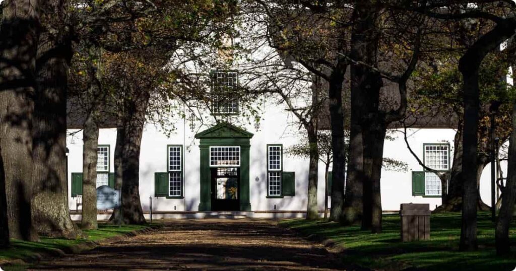 White Cape Dutch manor house surrounded by vineyards and mountains in the South Africa Cape Winelands
