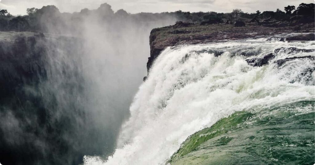 Swimmer at the edge of Devil's Pool looking over Victoria Falls into the gorge below, Zambia