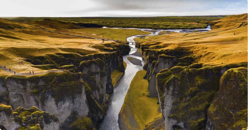 Lone hiker overlooking Reykjadalur steam valley Iceland at golden hour with geothermal mist rising from hillside