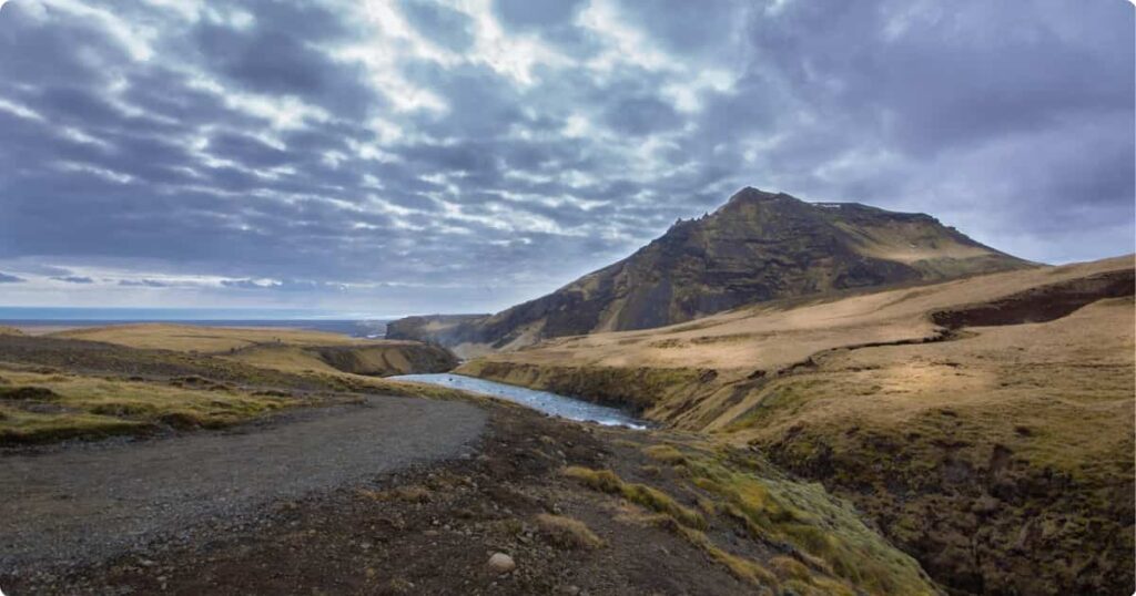 Reykjadalur Hot Springs: Iceland’s Best Budget Experience Hiker soaking in Reykjadalur geothermal thermal river surrounded by steam and green Icelandic valley