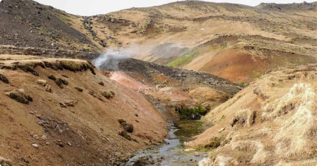 Natural geothermal thermal river in Reykjadalur valley Iceland with steam rising from water surface