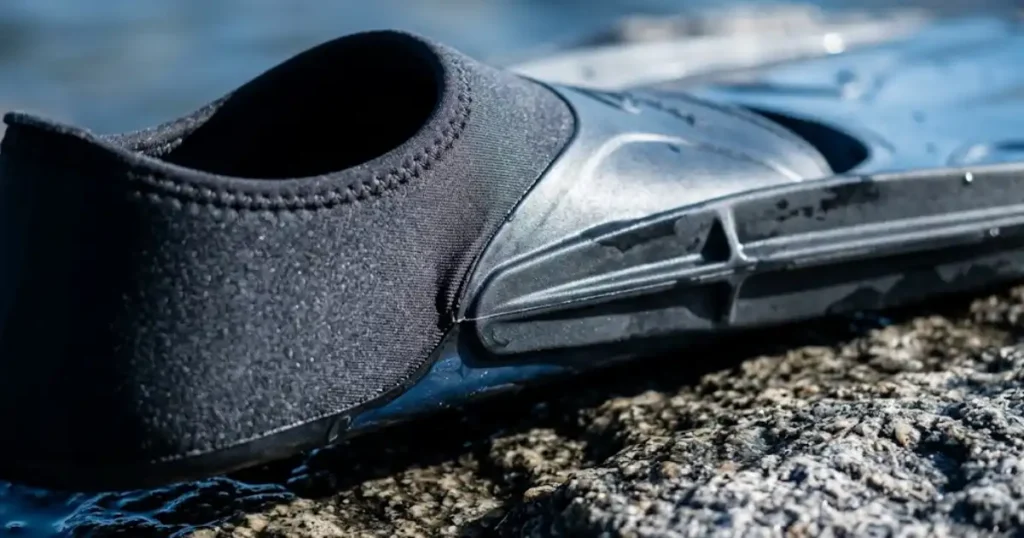  Close-up detail of travel snorkel fin foot pocket and blade on wet granite rock at waterline