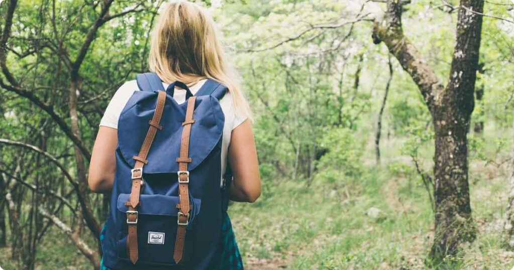 Solo female traveler walking confidently through a sunny urban street with a backpack