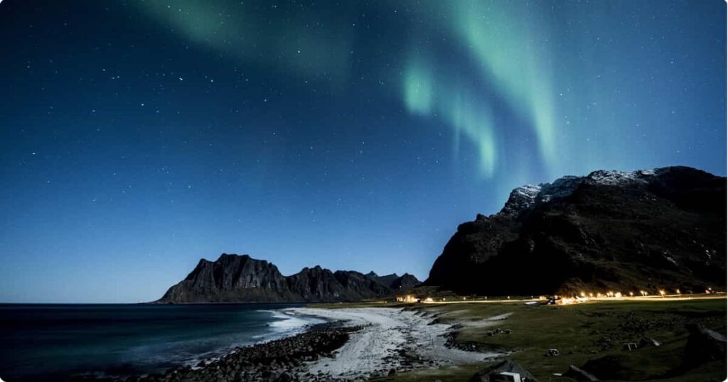 Northern lights over Iceland's snow-covered landscape in winter, ideal backdrop for full winter packing guide