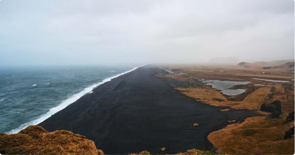 What to Wear in Iceland: Complete Packing Guide by Season Hiker in layered outdoor gear crossing Iceland's volcanic landscape in overcast conditions