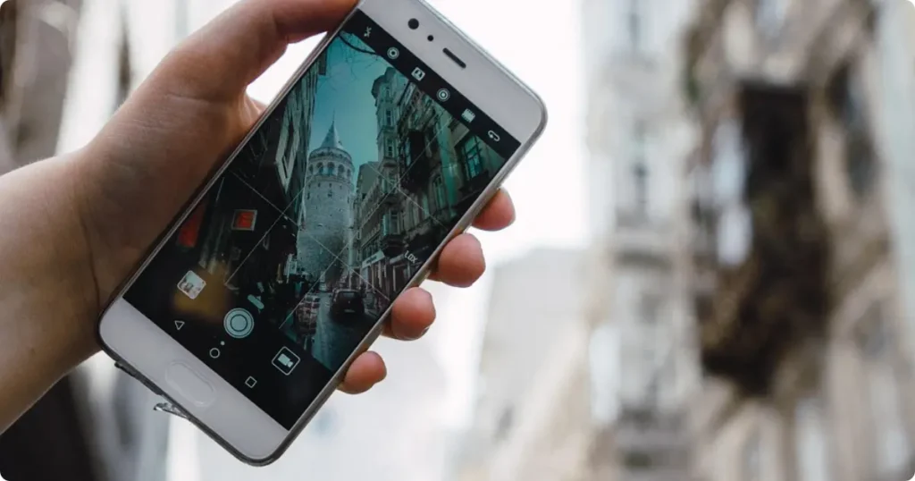 Hand holding smartphone showing 5G signal on European cobblestone street