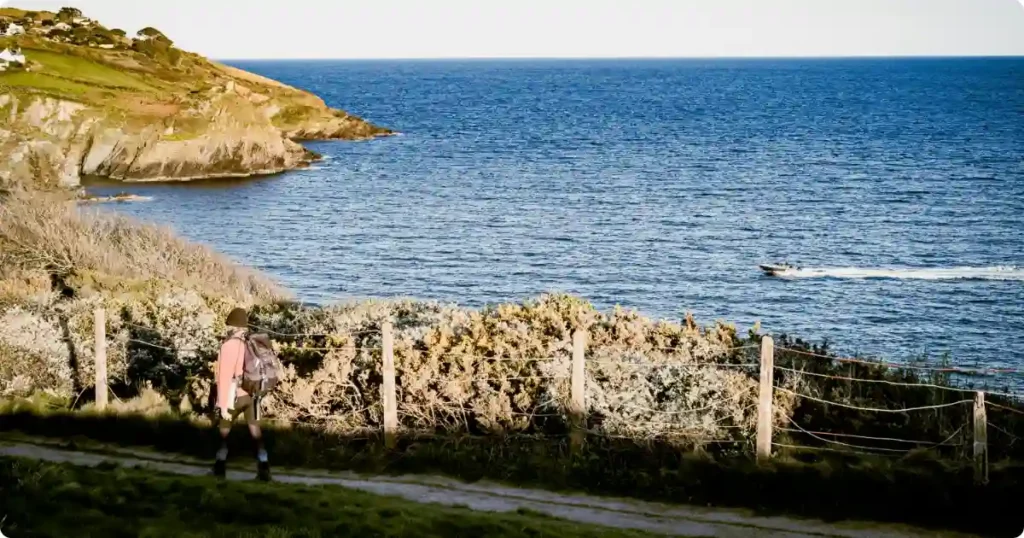 Hiker on clifftop trail above Algarve coast Portugal with turquoise Atlantic ocean below