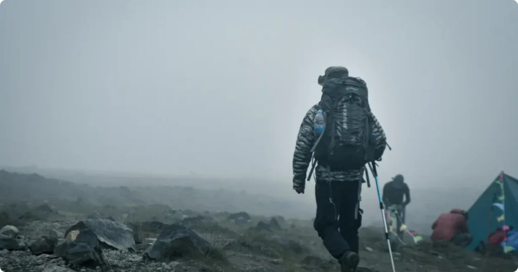 Backpacker using GPS navigation app mounted on pack strap while hiking rocky backcountry terrain