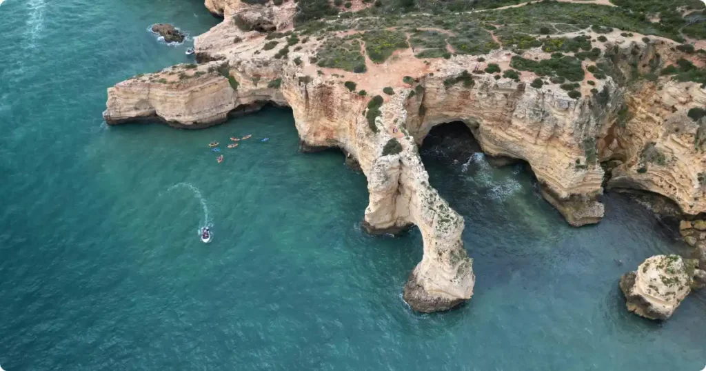Aerial view of kayaks paddling along golden Algarve limestone cliffs near Benagil Cave Portugal