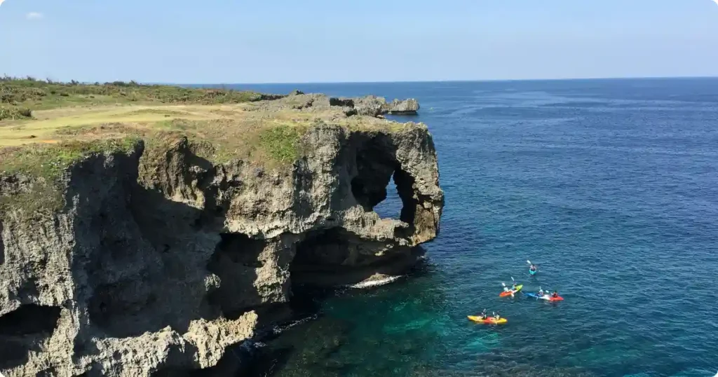 Sea kayaker paddling through rock arch into sunlit sea cave on Algarve coast Portugal
