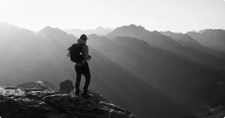Hiker crossing exposed mountain ridgeline at golden hour with dramatic valley drop — best adventure travel destinations