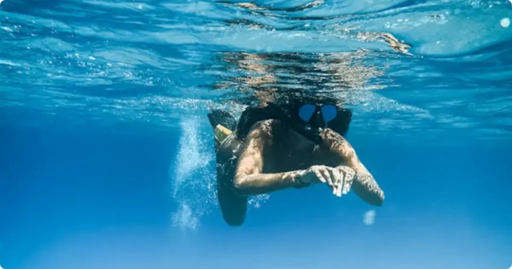 Snorkeler over tropical reef — best rash guard for snorkeling and swimming