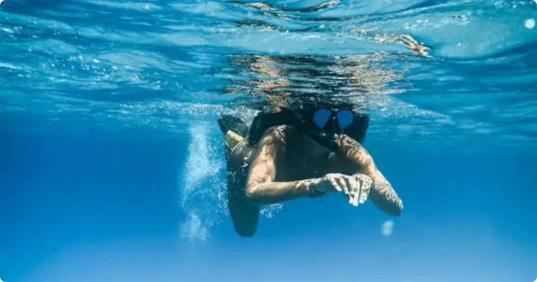 Snorkeler over tropical reef — best rash guard for snorkeling and swimming