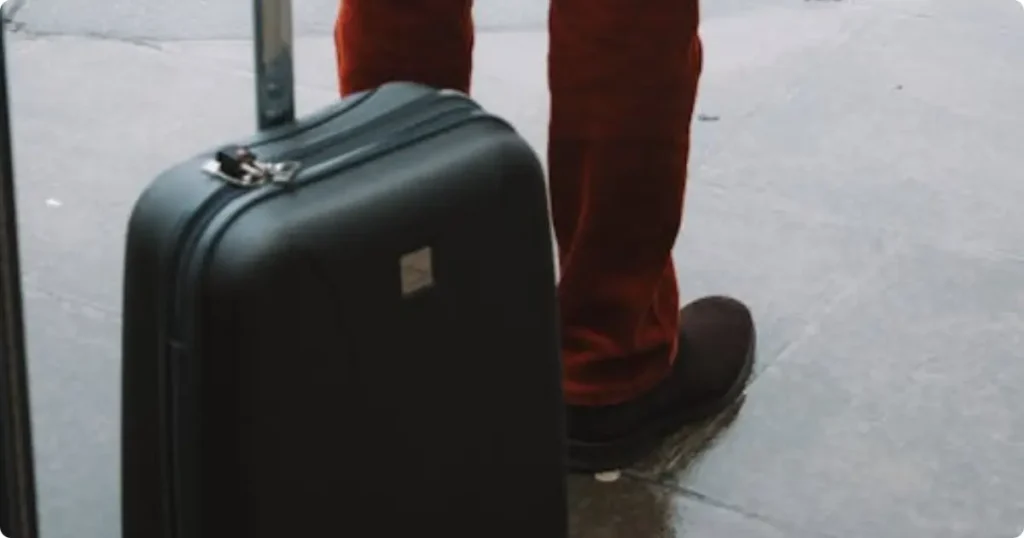 Traveler pulling carry-on suitcase through cobblestone European alley