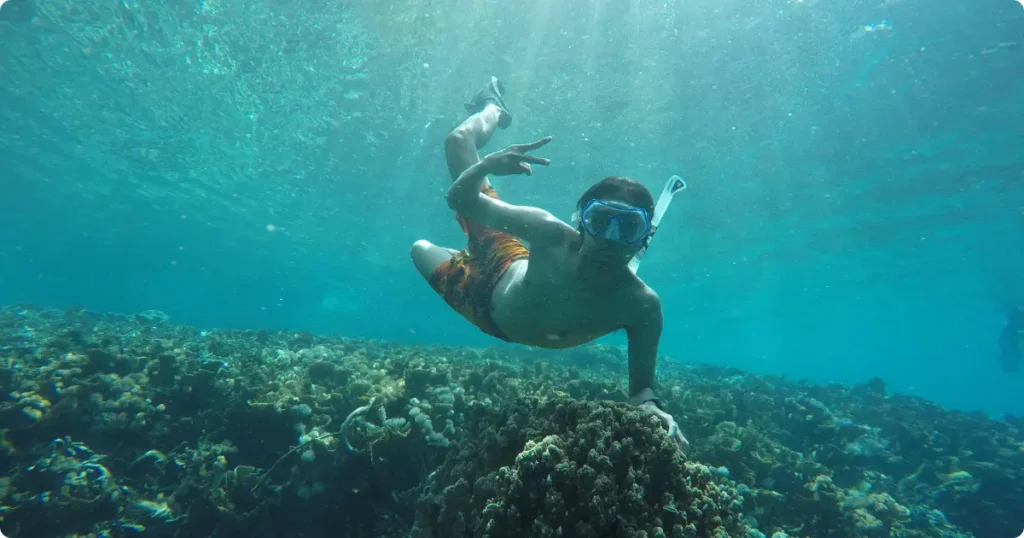 Beginner snorkeler floating above coral reef in clear turquoise water