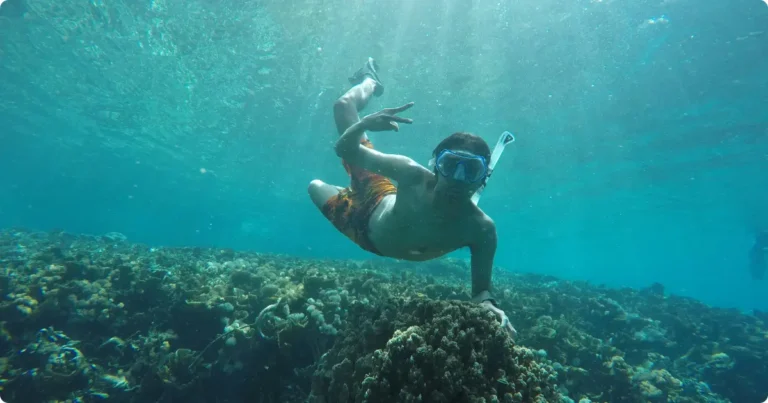 Beginner snorkeler floating above coral reef in clear turquoise water