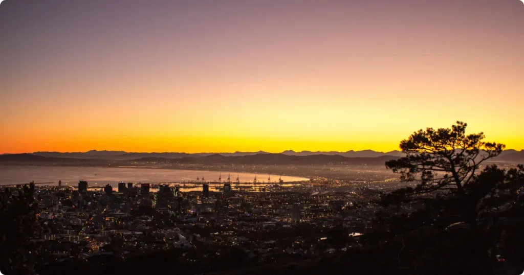 Hiker at Lion's Head summit overlooking Cape Town and Atlantic Ocean at sunrise