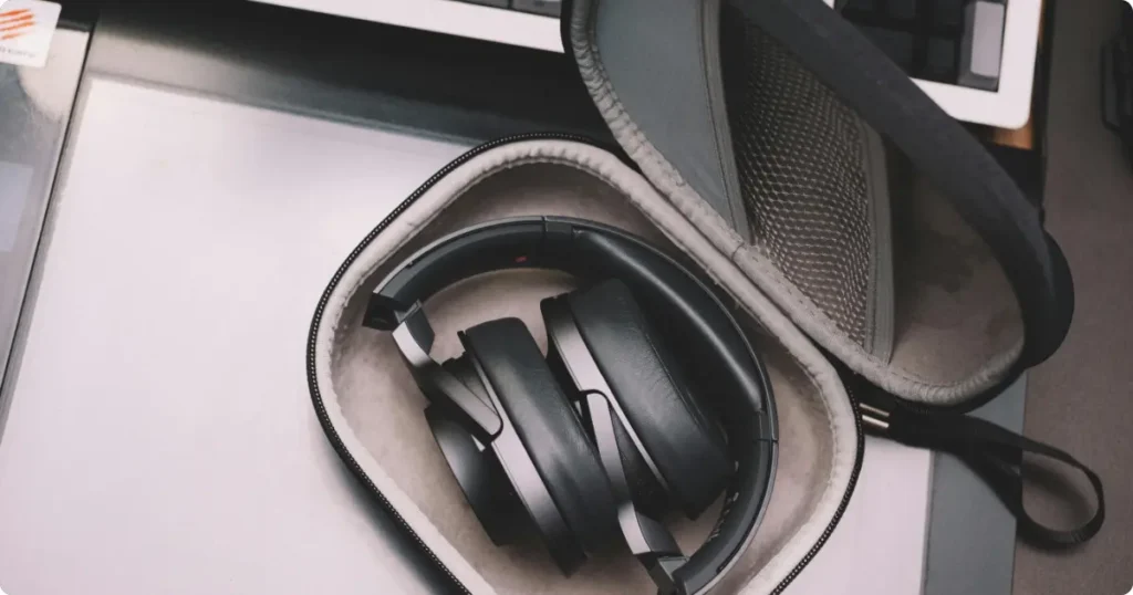 Foldable noise-cancelling headphones with compact carry case on wood surface showing travel-ready design