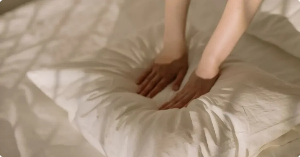 Hands compressing foam travel pillow to test density quality before long-haul flight