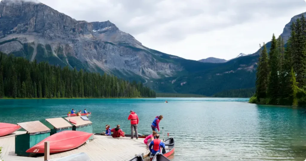 Traveler reviewing trip plan at mountain lake dock with kayak — how to match adventure travel insurance to your itinerary