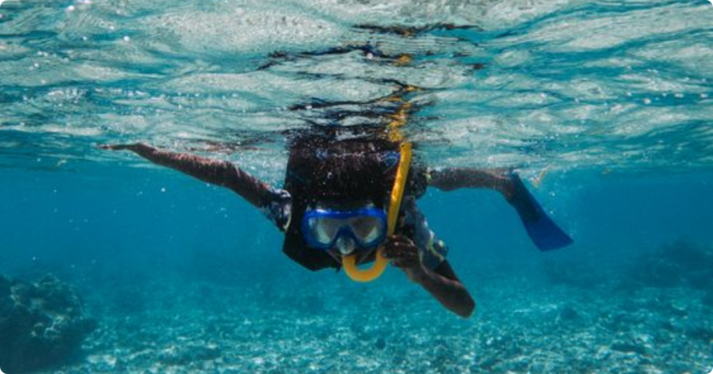 Snorkeler wearing waterproof belt bag at waist level wading into clear turquoise shallow water