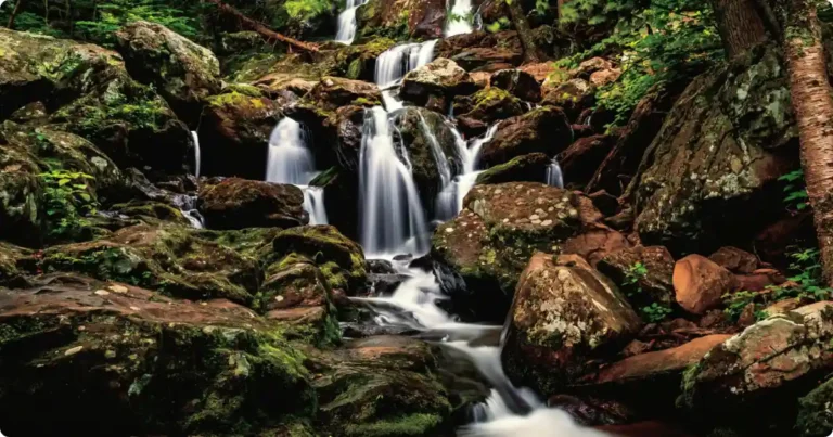Hiker standing beside waterfall in White Oak Canyon Shenandoah National Park Virginia