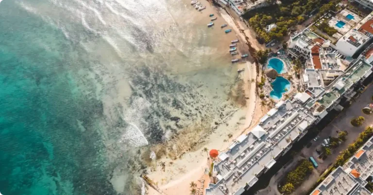 Puerto Morelos Mexico: The Laid-Back Alternative to Cancun Aerial view of Puerto Morelos Mexico coastline with turquoise reef waters and fishing boats on white sand beach