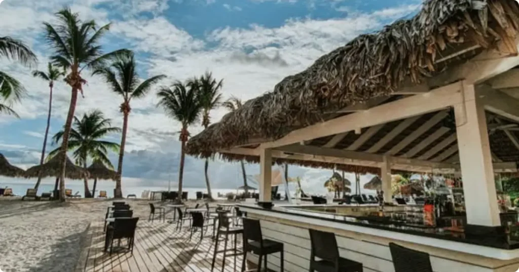 Shallow turquoise water beach bar scene at Secret Beach Belize with lounge chairs and palm shade