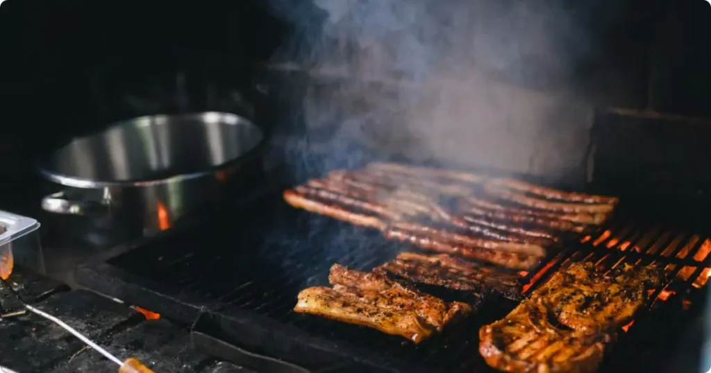 Boerewors sausage and lamb chops grilling over an open wood fire at a traditional South African braai