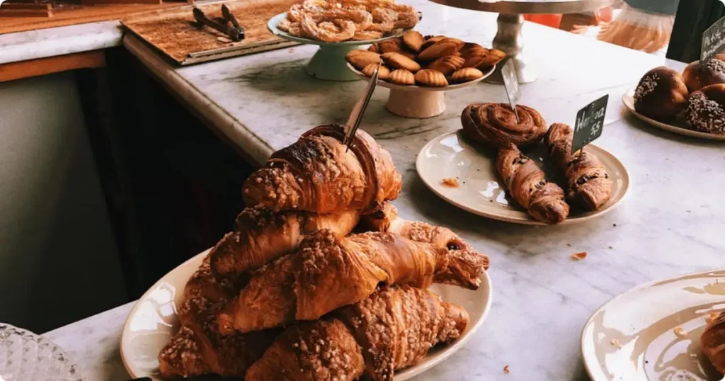 Golden croissants and macarons displayed at a Paris vegan patisserie counter, representing the city's plant-based bakery scene